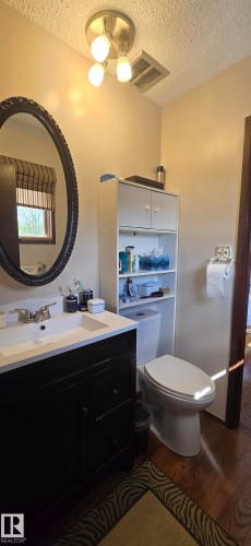 Bathroom featuring a dark wood-finish vanity with a white integrated sink and brushed nickel faucet - 5113 45 B Avenue, Vegreville, AB - Indoor Photo Showing Bathroom