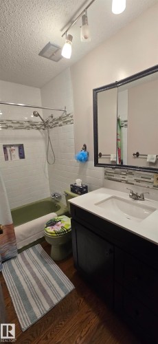 Bathroom featuring a modern vanity with a white countertop and integrated sink, a dark wood-finish cabinet, and a framed mirrored medicine cabinet - 5113 45 B Avenue, Vegreville, AB - Indoor Photo Showing Bathroom