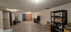 Spacious lower-level room featuring light wood-finish flooring, recessed lighting, and access to additional rooms - 