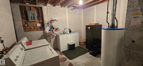Utility area featuring exposed ceiling joists, concrete flooring, and built-in white cabinetry with a light-colored countertop - 5113 45 B Avenue, Vegreville, AB - Indoor Photo Showing Basement