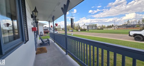 Covered front porch featuring a full-length railing, decorative balusters, and a concrete surface - 5113 45 B Avenue, Vegreville, AB - Outdoor
