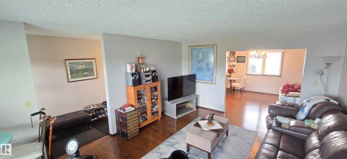 Living area featuring wood-finish flooring, light-toned wall paint, and an open doorway to a separate room - 5113 45 B Avenue, Vegreville, AB - Indoor Photo Showing Living Room With Fireplace