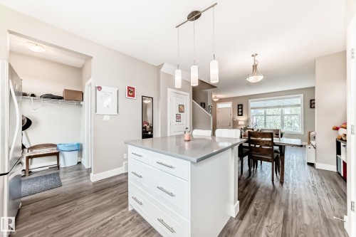 Kitchen island with a light-toned countertop, pendant lighting, wood-finish flooring, and recessed entryway closet - 2125 24 Street, Edmonton, AB - Indoor