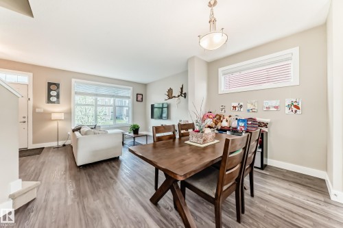 Open-concept living area featuring wood-finish flooring, a large window with blinds, and neutral wall tones - 2125 24 Street, Edmonton, AB - Indoor