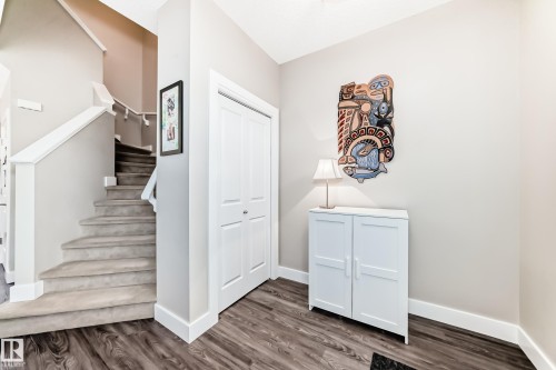 Entryway featuring wood-finish flooring, a carpeted staircase with white railings, and a white bi-fold closet - 2125 24 Street, Edmonton, AB - Indoor Photo Showing Other Room