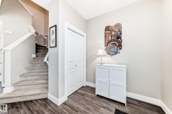 Entryway featuring wood-finish flooring, a carpeted staircase with white railings, and a white bi-fold closet - 