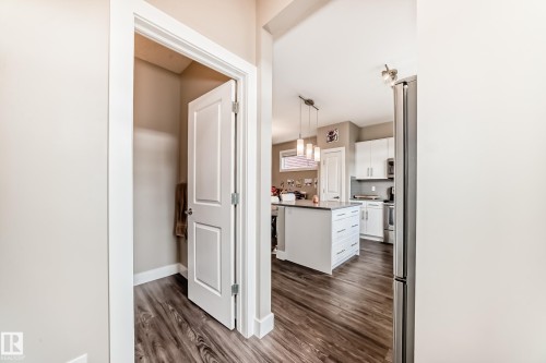 Kitchen featuring wood-finish flooring, a central island with countertop, pendant lighting, white cabinetry, and stainless steel appliances - 2125 24 Street, Edmonton, AB - Indoor