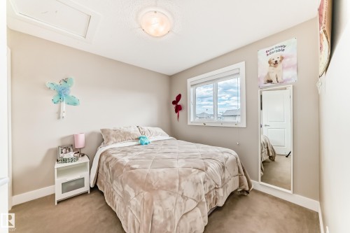 Neutral-toned carpeting extends throughout this room, featuring a white window frame with multiple panes - 2125 24 Street, Edmonton, AB - Indoor Photo Showing Bedroom
