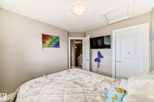 Neutral-toned room featuring a built-in wall-mounted television, white panel doors, and a ceiling-mounted light fixture - 2125 24 Street, Edmonton, AB - Indoor Photo Showing Bedroom