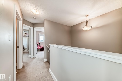 Hallway featuring neutral-toned walls, plush carpeting, white trim, a decorative pendant light fixture, and an overhead flush-mount light - 2125 24 Street, Edmonton, AB - Indoor Photo Showing Other Room