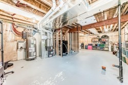 Unfinished basement featuring a painted concrete floor, exposed wood ceiling joists, and visible HVAC ductwork - 