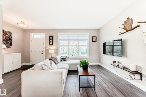 Spacious living area featuring wood-finish flooring, light neutral wall tones, and a large window with blinds - 2125 24 Street, Edmonton, AB - Indoor Photo Showing Living Room
