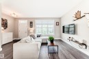 Spacious living area featuring wood-finish flooring, light neutral wall tones, and a large window with blinds - 2125 24 Street, Edmonton, AB  - Indoor Photo Showing Living Room 