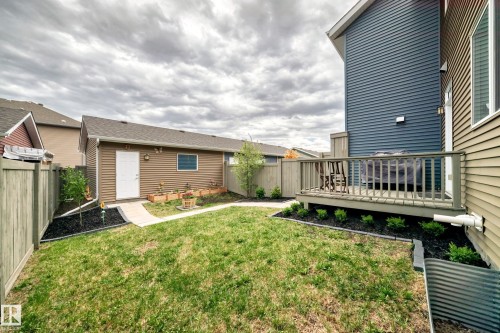 Spacious backyard featuring a wooden deck, a detached garage with exterior lighting, and a paved walkway - 2125 24 Street, Edmonton, AB - Outdoor With Deck Patio Veranda With Exterior