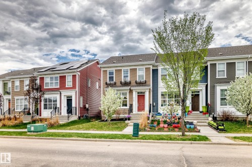Two-story townhome featuring a red siding facade, white trim, and a black front door - 2125 24 Street, Edmonton, AB - Outdoor With Facade