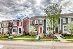 Two-story townhome featuring a red siding facade, white trim, and a black front door - 
