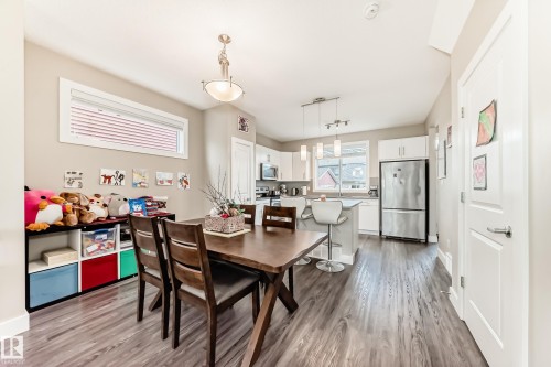 Open-concept living space featuring wood-finish flooring, a contemporary kitchen, and built-in white cabinetry - 2125 24 Street, Edmonton, AB - Indoor Photo Showing Dining Room