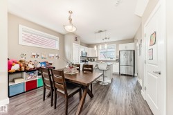 Open-concept living space featuring wood-finish flooring, a contemporary kitchen, and built-in white cabinetry - 