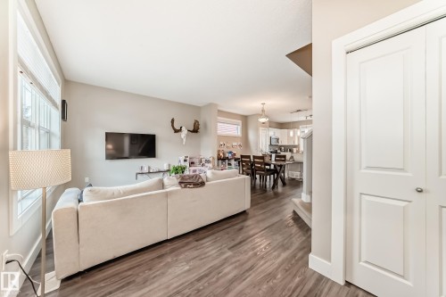 Spacious room featuring wood-finish flooring, light neutral wall tones, and a large window with horizontal blinds - 2125 24 Street, Edmonton, AB - Indoor Photo Showing Living Room