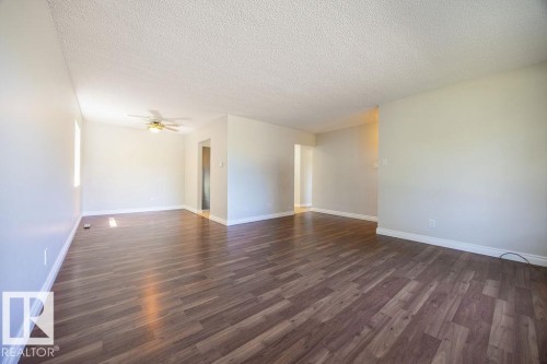 Spacious interior featuring wood-finish flooring, light-toned walls, and a ceiling fan with integrated lighting - 8714 164 Street, Edmonton, AB 