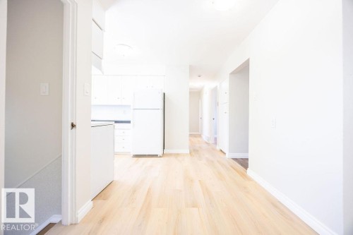 Kitchen area featuring light wood-finish flooring, white cabinetry, and white appliances - 8714 164 Street, Edmonton, AB 