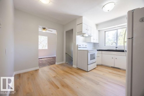 Bright kitchen featuring ample white cabinetry, a white electric range, and a large window above the sink - 8714 164 Street, Edmonton, AB 
