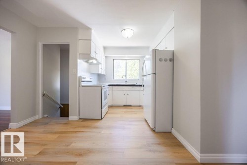 Kitchen featuring white cabinetry, a black countertop, and a window above the sink - 8714 164 Street, Edmonton, AB 