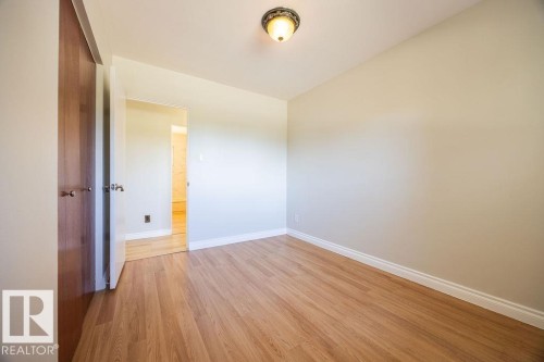 Room featuring wood-finish flooring, light-toned walls, white baseboards, and a flush-mount ceiling light fixture - 8714 164 Street, Edmonton, AB 