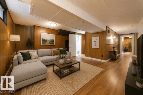 Spacious recreational room featuring wood-panel walls, wood-finish flooring, and a drop ceiling with integrated lighting. Virtually Staged Photo. - 8714 164 Street, Edmonton, AB 