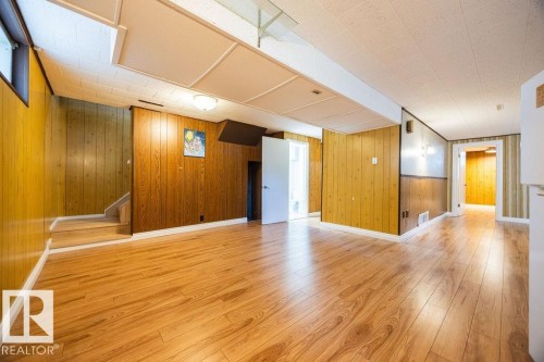 Spacious interior featuring wood-finish flooring, wood paneling, white trim, recessed lighting, and a drop ceiling - 8714 164 Street, Edmonton, AB 