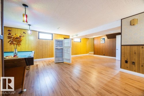 Expansive lower level featuring wood-finish flooring, recessed windows, and paneled walls - 8714 164 Street, Edmonton, AB 