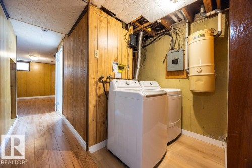 Dedicated laundry area featuring wood-finish flooring, wood paneling, and a drop ceiling - 8714 164 Street, Edmonton, AB 