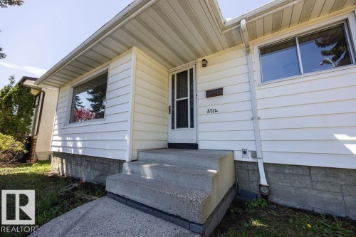 Front entrance featuring white horizontal siding, a concrete entryway, and a storm door - 8714 164 Street, Edmonton, AB 