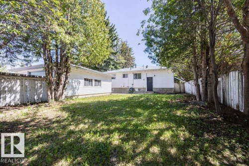 Expansive grassy yard with mature trees along the perimeter and a solid privacy fence - 8714 164 Street, Edmonton, AB 