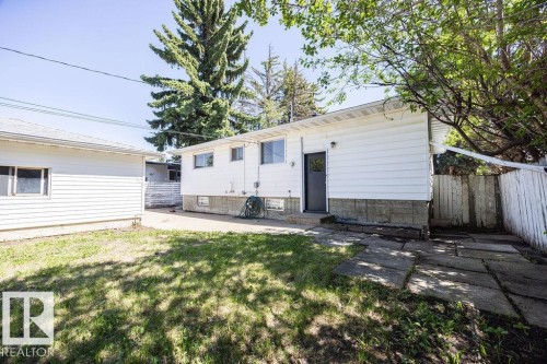 Rear exterior with white siding and gray foundation, featuring an entry door and two windows - 8714 164 Street, Edmonton, AB 