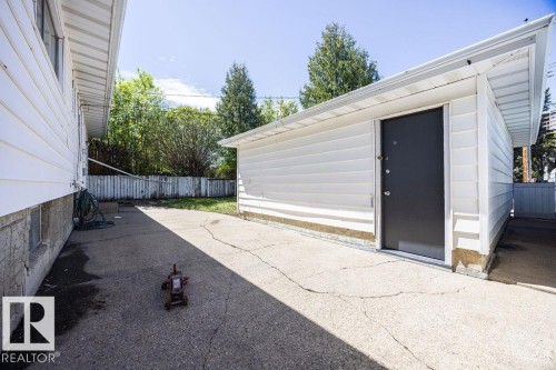 Detached garage featuring white siding, a dark entry door, and an angled roofline - 8714 164 Street, Edmonton, AB 