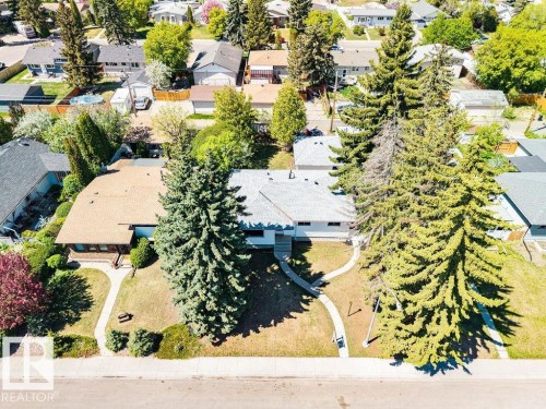 Single-story residence with a light-colored shingle roof, accompanied by mature evergreen trees - 8714 164 Street, Edmonton, AB 