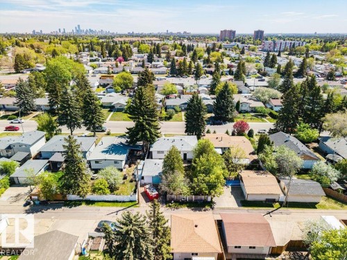 Aerial perspective of a residential neighborhood featuring established homes with mature trees and a distant cityscape - 8714 164 Street, Edmonton, AB 
