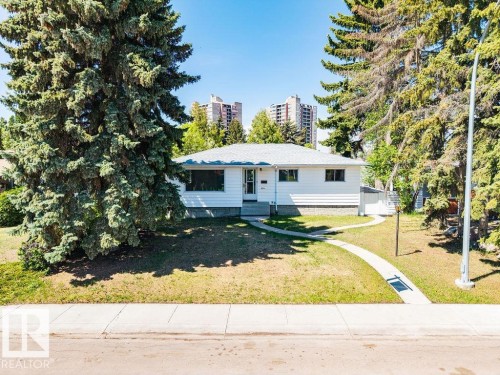 White single-story dwelling featuring a light gray shingled roof, white siding, and dark-trimmed windows - 8714 164 Street, Edmonton, AB 