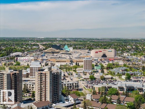 Urban landscape featuring a prominent shopping complex with a distinctive curved facade, multi-level residential buildings, extensive surface parking areas, and surrounding green spaces - 8714 164 Street, Edmonton, AB 