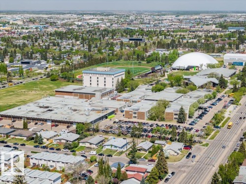 Aerial perspective showcasing a residential area with mixed-use buildings, mature trees, and extensive green spaces - 8714 164 Street, Edmonton, AB 