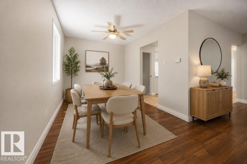 Open-concept dining area featuring wood-finish flooring, a contemporary ceiling fan, and ample natural light from a window. Photo Virtually Staged. - 8714 164 Street, Edmonton, AB 