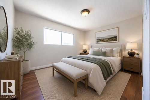 Spacious room featuring wood-finish flooring, a contemporary window, and recessed lighting. Photo Virtually Staged. - 8714 164 Street, Edmonton, AB 