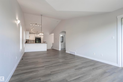 Spacious open-concept living area featuring wood-finish flooring, vaulted ceilings, and a large sliding glass door - 738 Kananaskis Drive, Devon, AB - Indoor