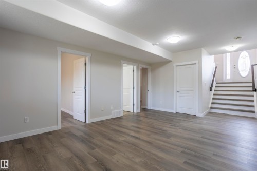 Spacious room featuring wood-finish flooring, light grey walls, white trim, and multiple white doors - 738 Kananaskis Drive, Devon, AB - Indoor Photo Showing Other Room