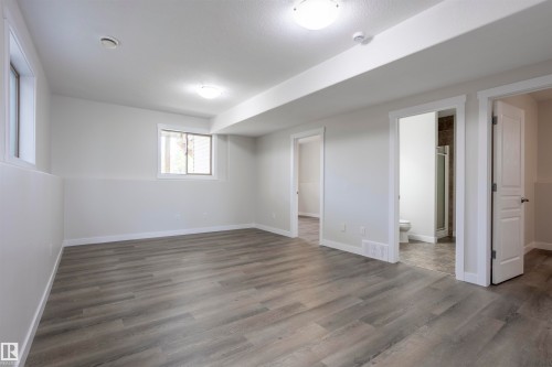 Spacious room featuring wood-finish flooring, light grey walls, and multiple windows - 738 Kananaskis Drive, Devon, AB - Indoor Photo Showing Other Room
