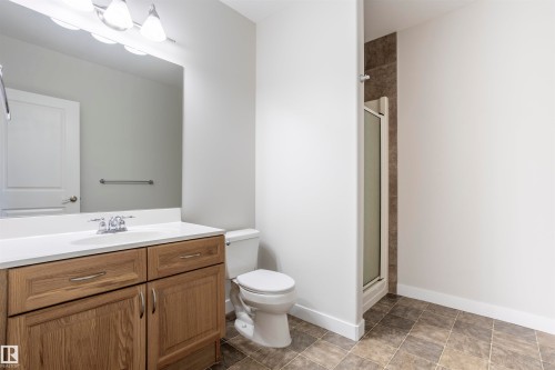 Bathroom featuring wood-finish vanity with countertop sink, chrome faucet, and rectangular mirror - 738 Kananaskis Drive, Devon, AB - Indoor Photo Showing Bathroom