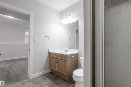 Bathroom featuring a wood-finish vanity with a white countertop, an undermount sink, and a toilet - 738 Kananaskis Drive, Devon, AB - Indoor Photo Showing Bathroom