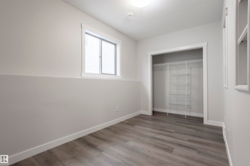 Room featuring wood-finish flooring, a window with horizontal blinds, and a closet with built-in wire shelving - 738 Kananaskis Drive, Devon, AB - Indoor Photo Showing Other Room