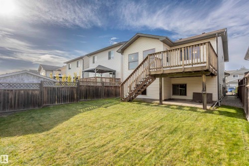 Private backyard featuring a wooden privacy fence, a raised wood deck with staircase, and a ground-level concrete patio - 738 Kananaskis Drive, Devon, AB - Outdoor With Deck Patio Veranda